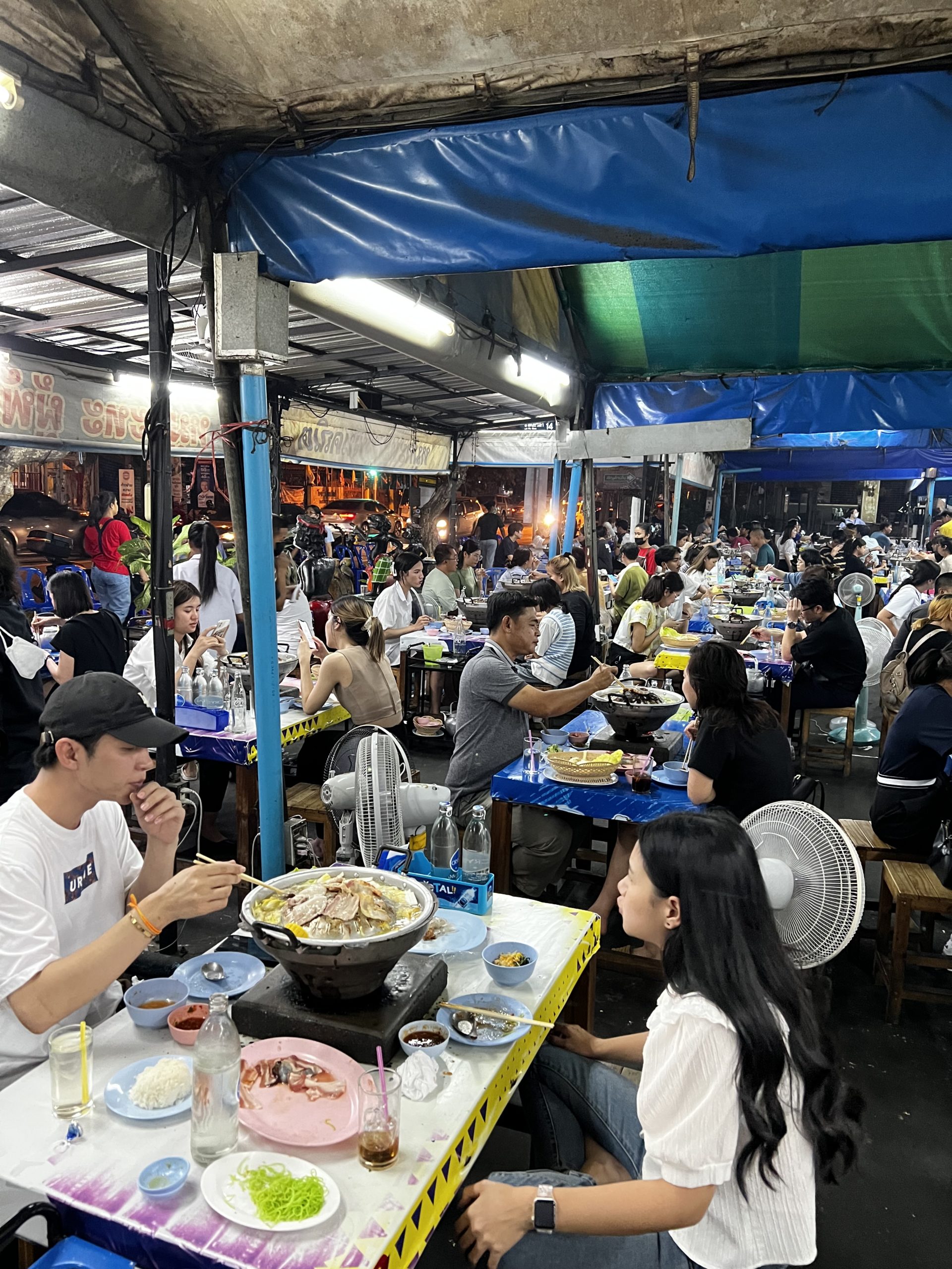 Moo Kra Tha in Bangkok, Menschen sitzen an Tischen, in der Mitte der Tische ein Thai BBQ Grill